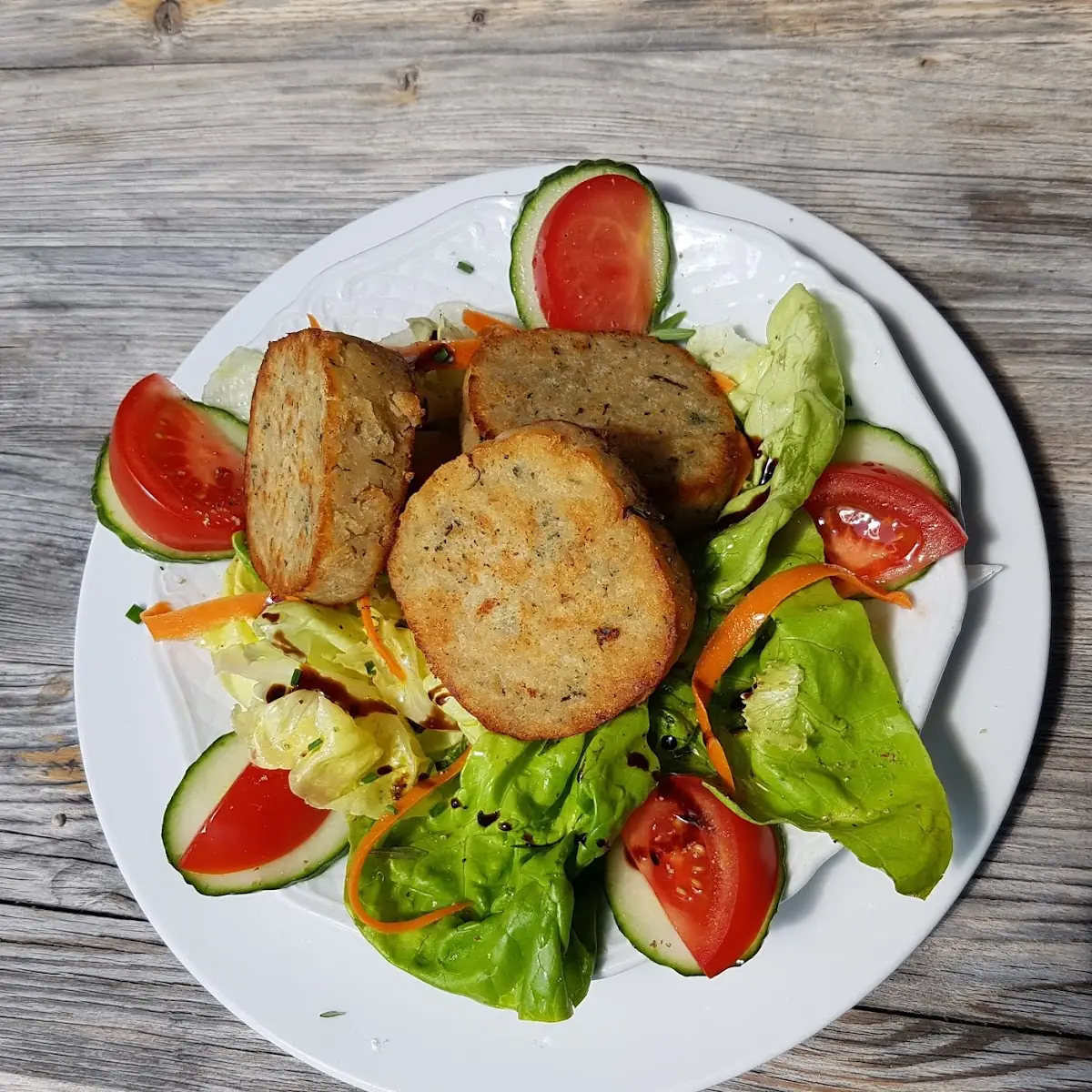 Kräuterserviettenknödel Auf Blattsalat Mit Tomaten Und Gurken