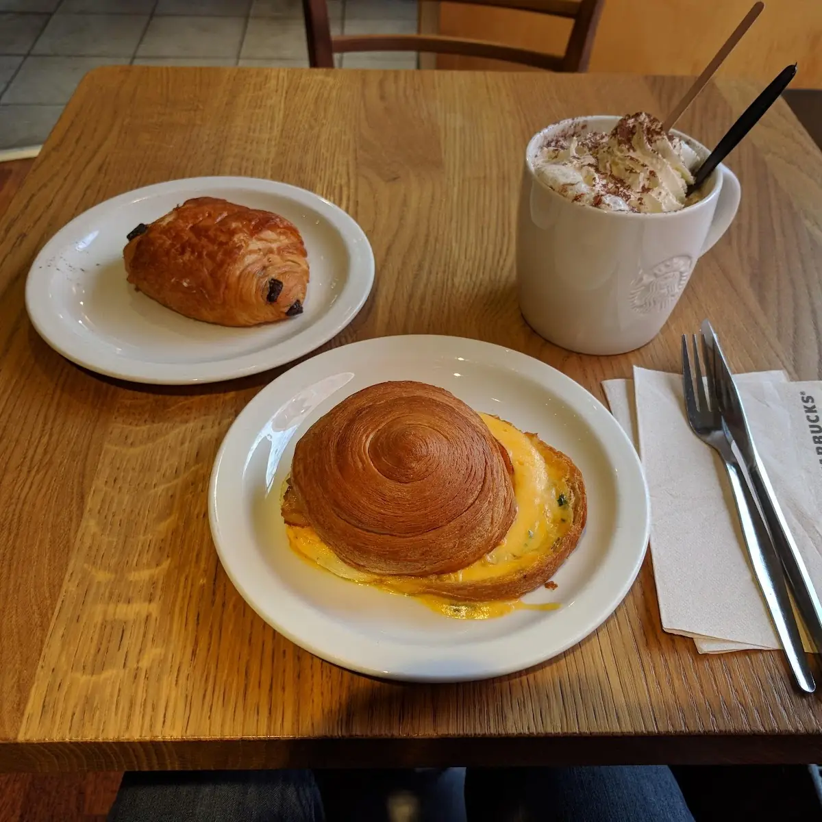 A Croissant Roll with Bacon and Egg a Pain Au Chocolat and a Cappuccino with Extra Cream