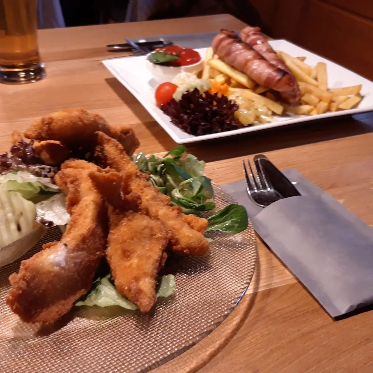 Vorne Salat Mit Panierten Hähnchenteilen Im Hintergrund Berner Würstel Mit Pommes