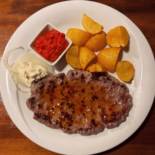Pljeskavica (vom Grill) mit Bratkartoffeln, Ajvar und Zwiebelscheiben