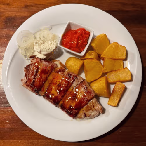 Hausschnitzel (vom Grill) im Speckmantel gefüllt mit Käse dazu Bratkartoffeln, Ajvar und Zwiebelscheiben