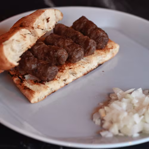 Cevapcici auf Fladenbrot mit Zwiebeln (5 Stück)