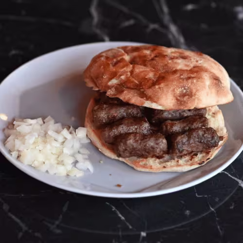 Cevapcici auf Fladenbrot mit Zwiebeln (10 Stück)